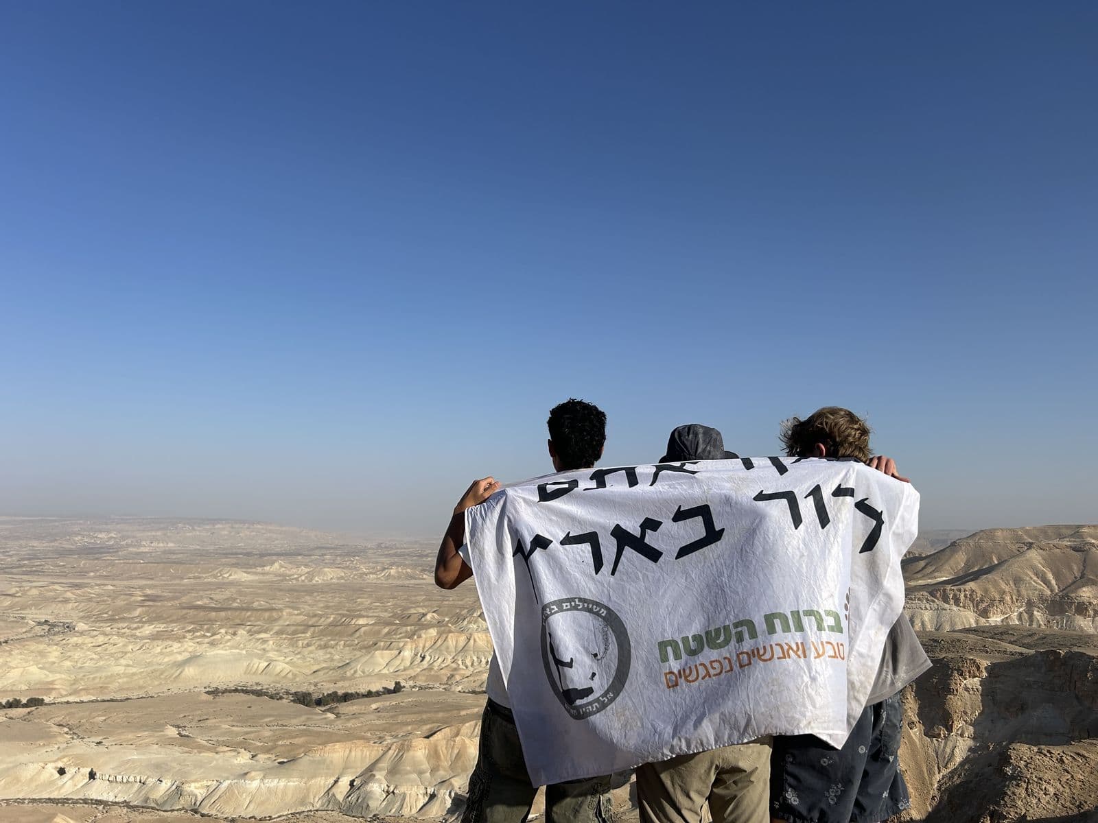 שניים מחזיקים דגל ברוח השטח מול נוף מדברי רחב