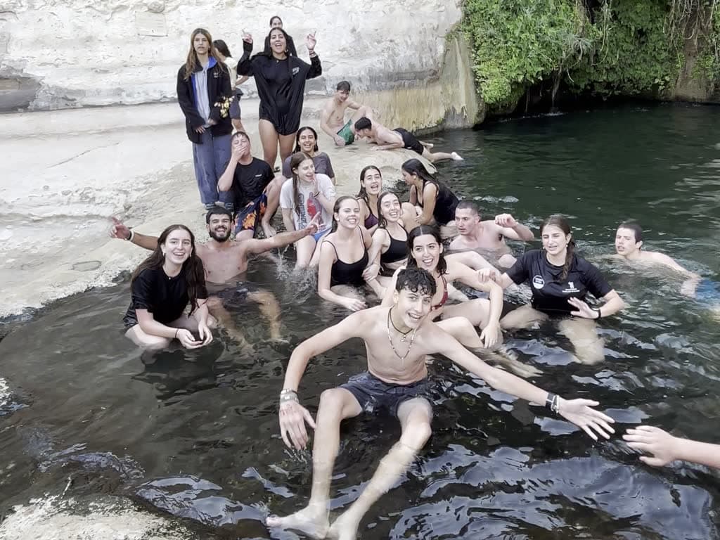 כל הקבוצה יחד במעיין בסוף יום מסע, מנופפים למצלמה