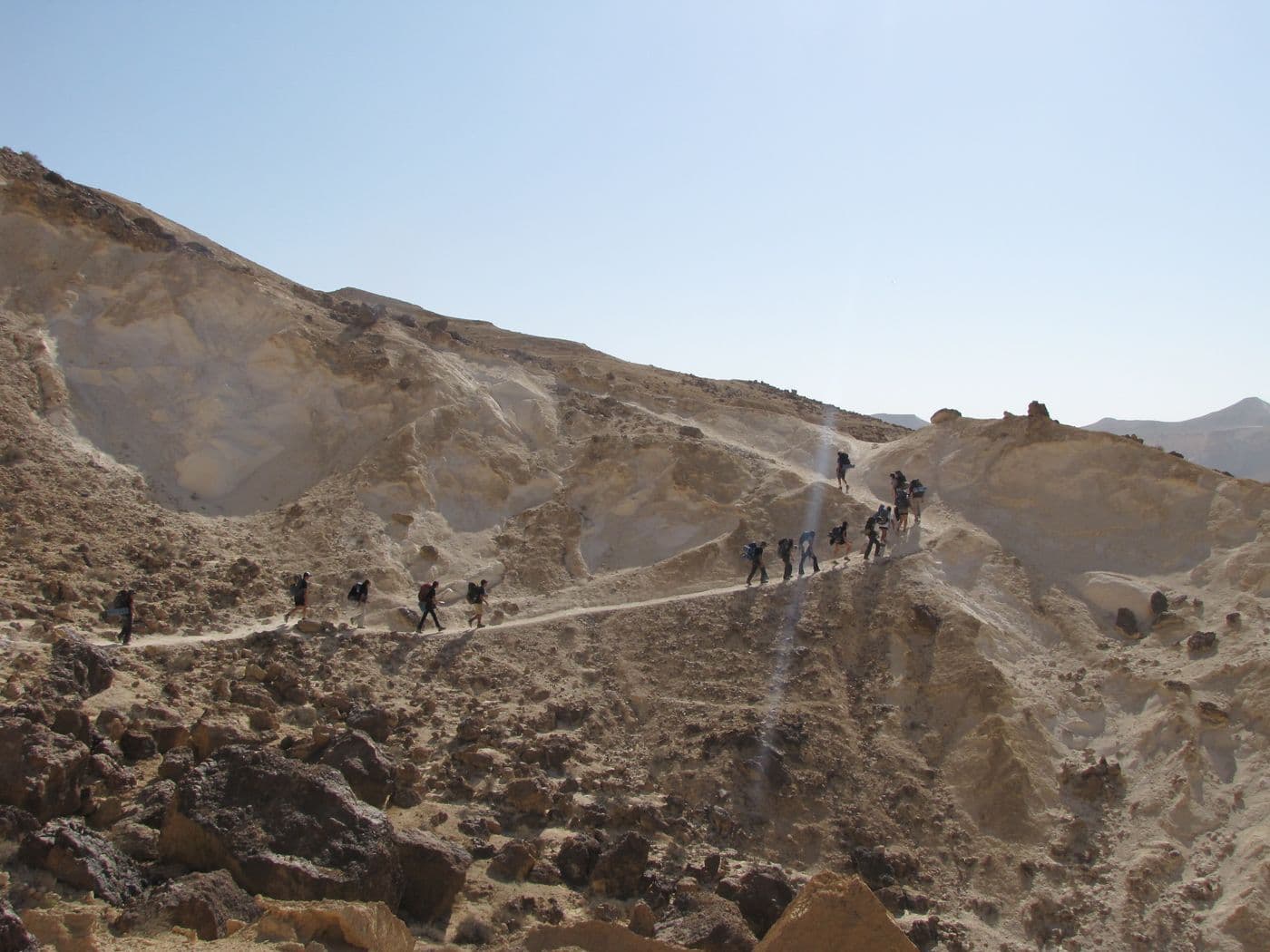 Participants walking single file along a desert ridge